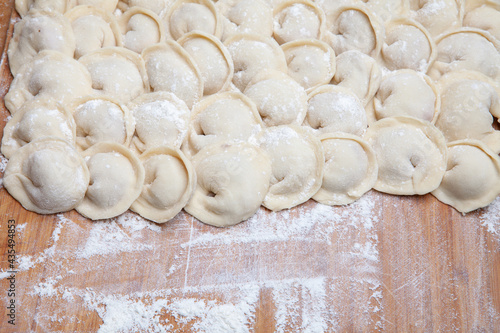 homemade dumplings with meat on a floured board.