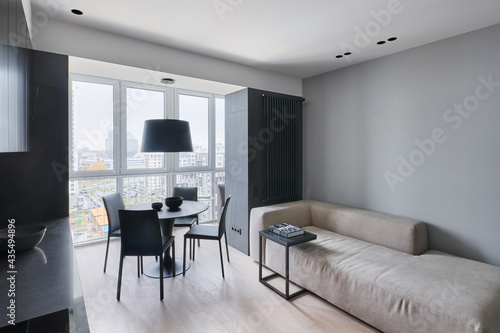 Minimalist stylish sofa in the dining area with leather chairs in the studio in monochrome colors