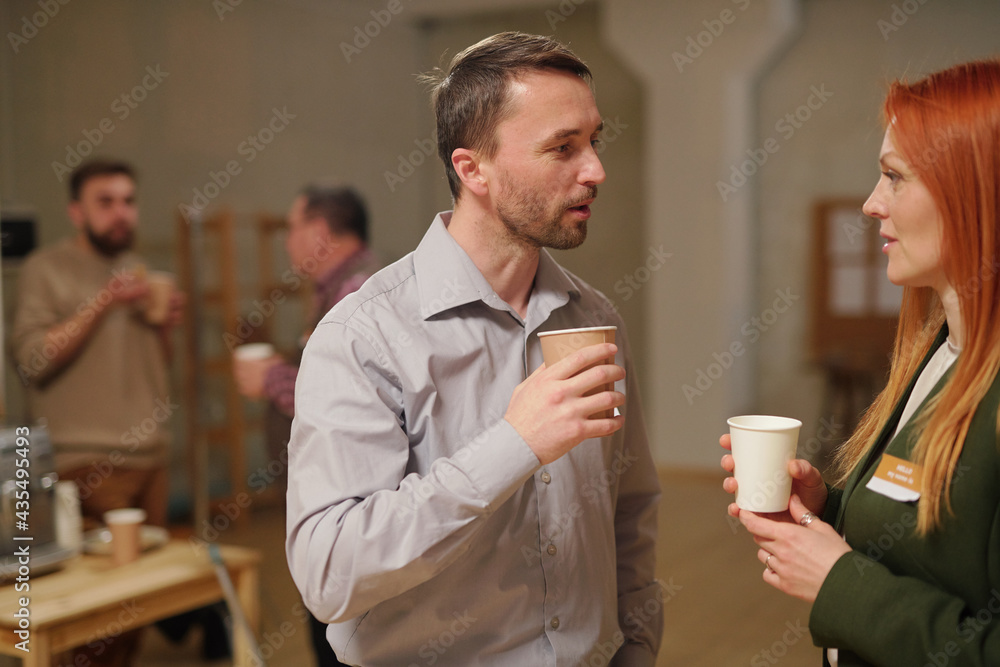 Middle aged man and woman with drinks interacting after session