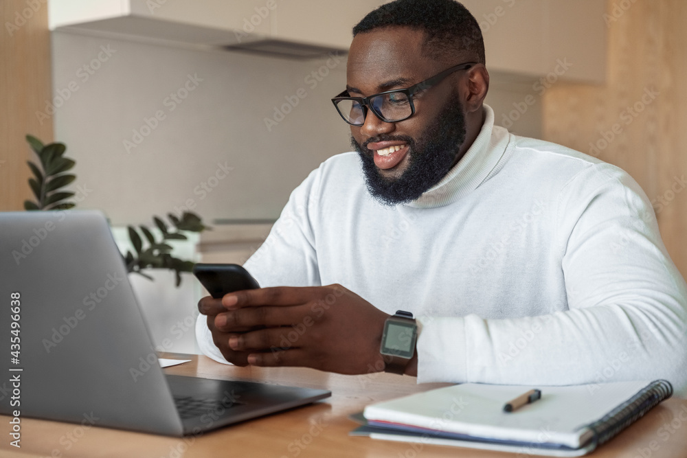 Young smiling african american man relaxing using laptop and mobile phone Young smiling african american man relaxing using laptop and mobile phone
