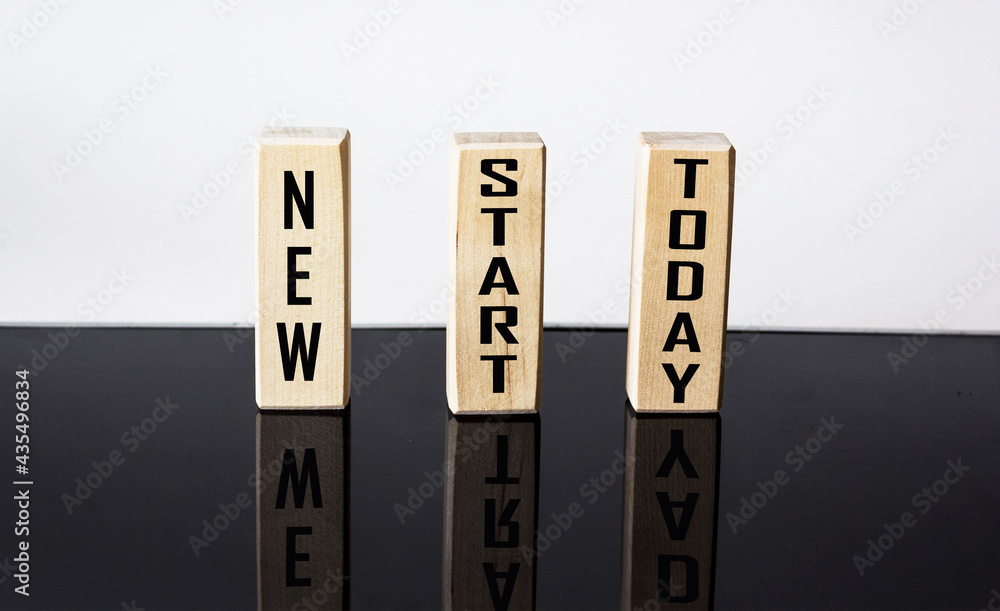 New start today. Concept on wooden blocks and white and black background New start today. Concept on wooden blocks and white and black background