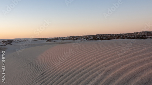 Soft rays of sunlight visible on pattern of sand dune ripples