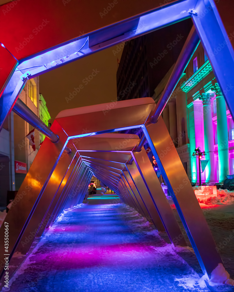 Naklejka premium Brightly lit artistic pathway at night - colourful art installation in winter