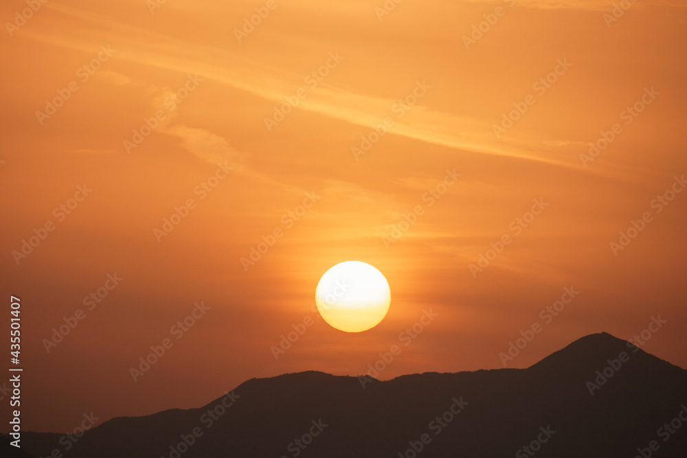 Fototapeta premium Sunset sky with orange clouds. A beautiful, colorful, abstract mountain landscape with sun in a orange tonality. Nature sky background. Sky sunset in the morning with colorful orange sunlight.