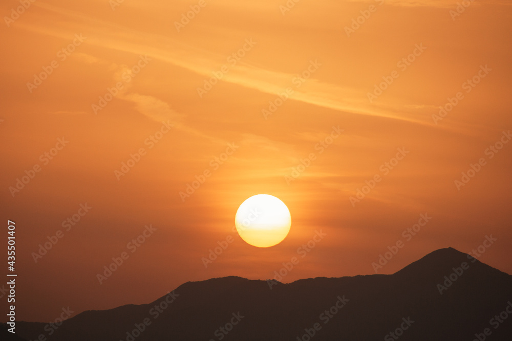 Sunset sky with orange clouds. A beautiful, colorful, abstract mountain landscape with sun in a orange tonality. Nature sky background. Sky sunset in the morning with colorful orange sunlight.