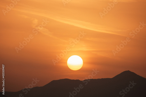 Sunset sky with orange clouds. A beautiful, colorful, abstract mountain landscape with sun in a orange tonality. Nature sky background. Sky sunset in the morning with colorful orange sunlight.