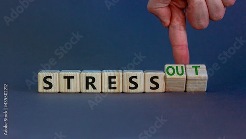 Stress or stress out symbol. Businessman turns cubes, changes words 'stress' to 'stress out'. Beautiful grey background. Medical, psychological, stress or stress out concept. Copy space.