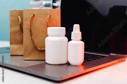 Online pharmacy. Paper bags with prescription drugs and pills and white conteiners on laptop photo