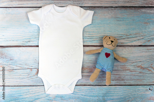 White baby bodysuit mockup with toy on wooden background. Styled stock photography. Mock up