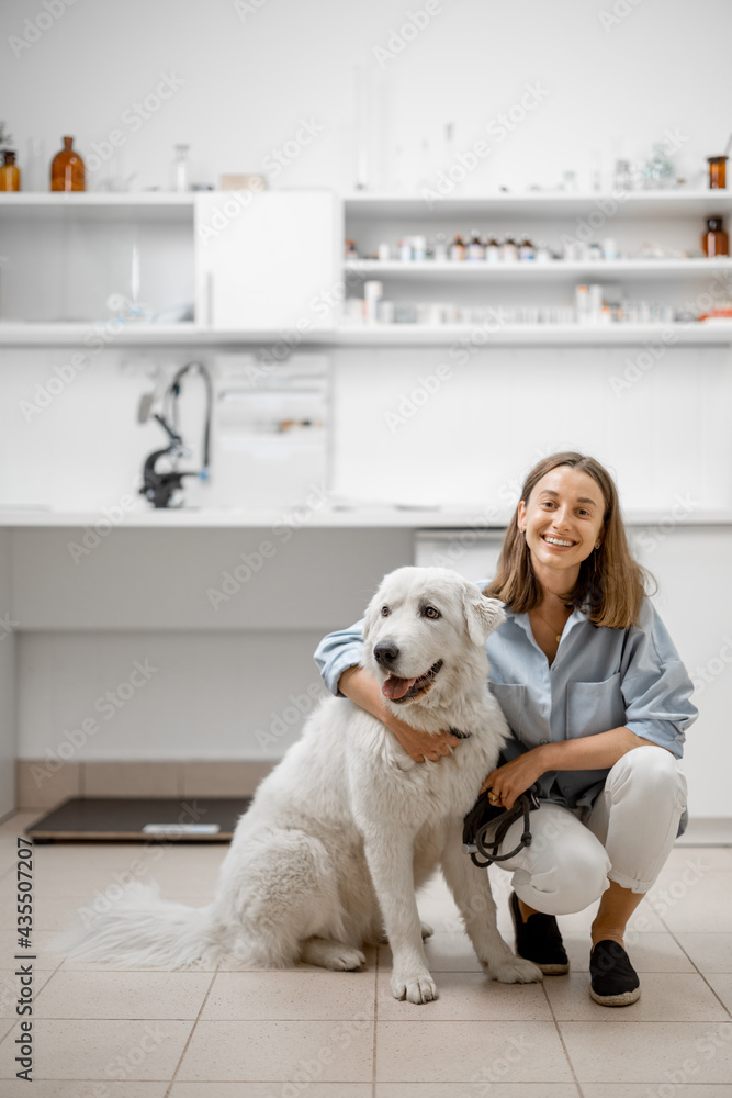 A portrait of young female owner with big white dog waiting for the veterinarian in veterinary clinic. Pet care concept