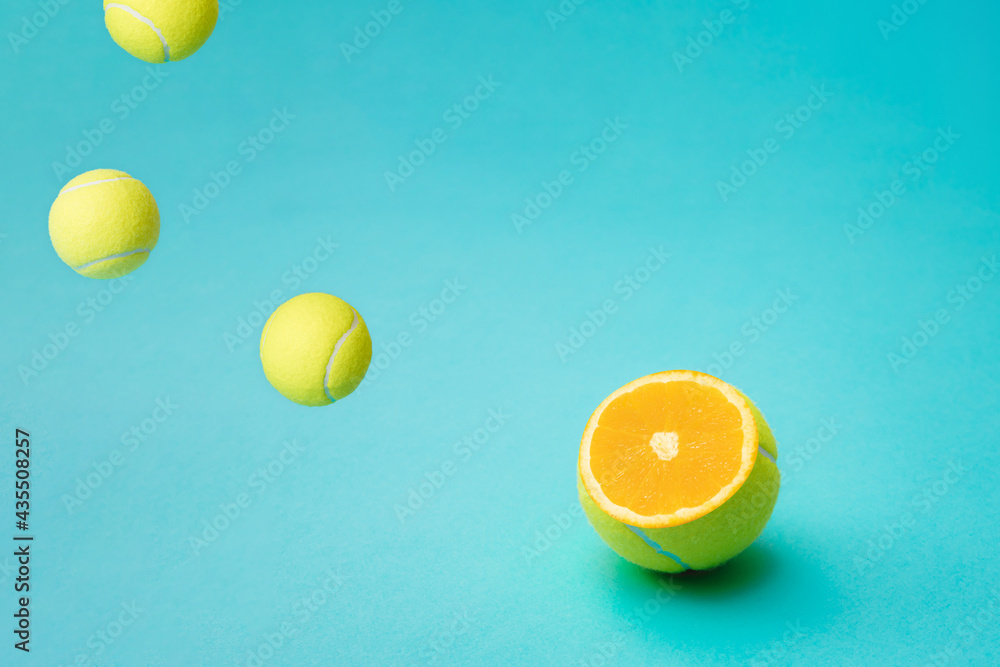 Cut in half a green tennis ball. An orange in a tennis ball and balls falling next to it.