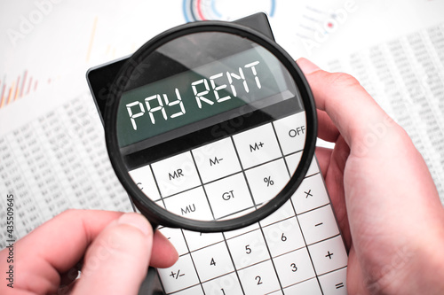 The word pay rent is written on the calculator. Business man holding a calculator in his hand.