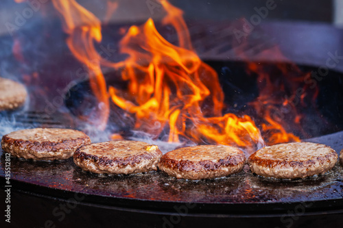 Burgers for hamburger prepared on bbq grill Close-up, barbecue outdoors with fire flame