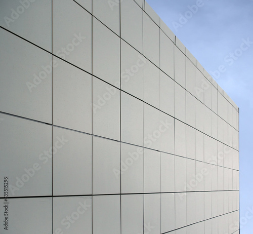 geometric blue metallic cladding modern facade in perspective view with blue sky