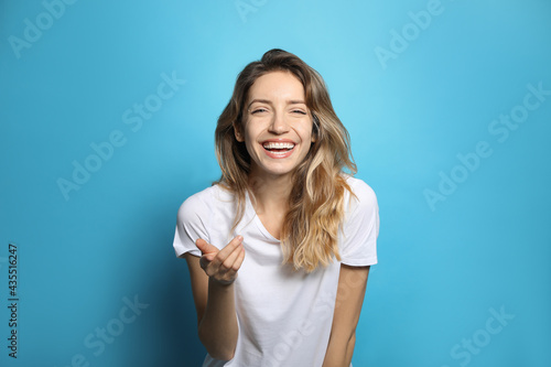 Vászonkép Cheerful young woman laughing on light blue background