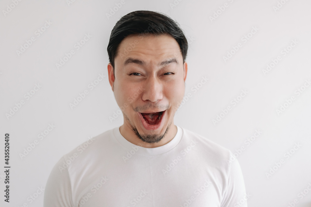 Funny grin smile face of Asian man in white t-shirt isolated on white wall. Funny grin smile face of Asian man in white t-shirt isolated on white wall.