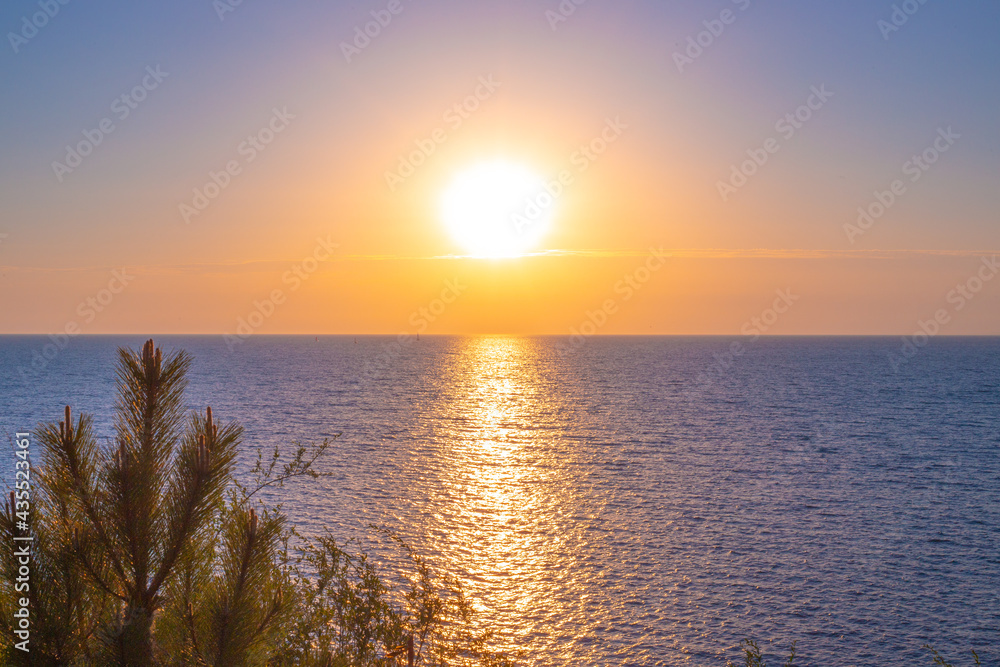 Fototapeta premium Walkway in the sea from the sun at sunset. Seascape. Summer vacation and travel