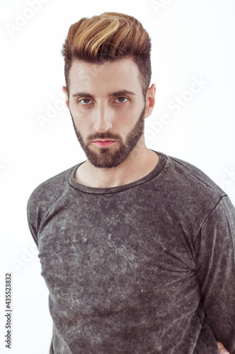 Chico joven de barba posa de perfil con remera  photo