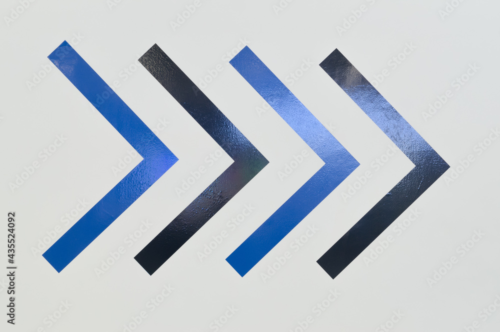 Black and blue arrow sticker signs in boomerang shape on the wall pointing to the right side, colorful painted art symbol backdrop or background Black and blue arrow sticker signs in boomerang shape on the wall pointing to the right side, colorful painted art symbol backdrop or background