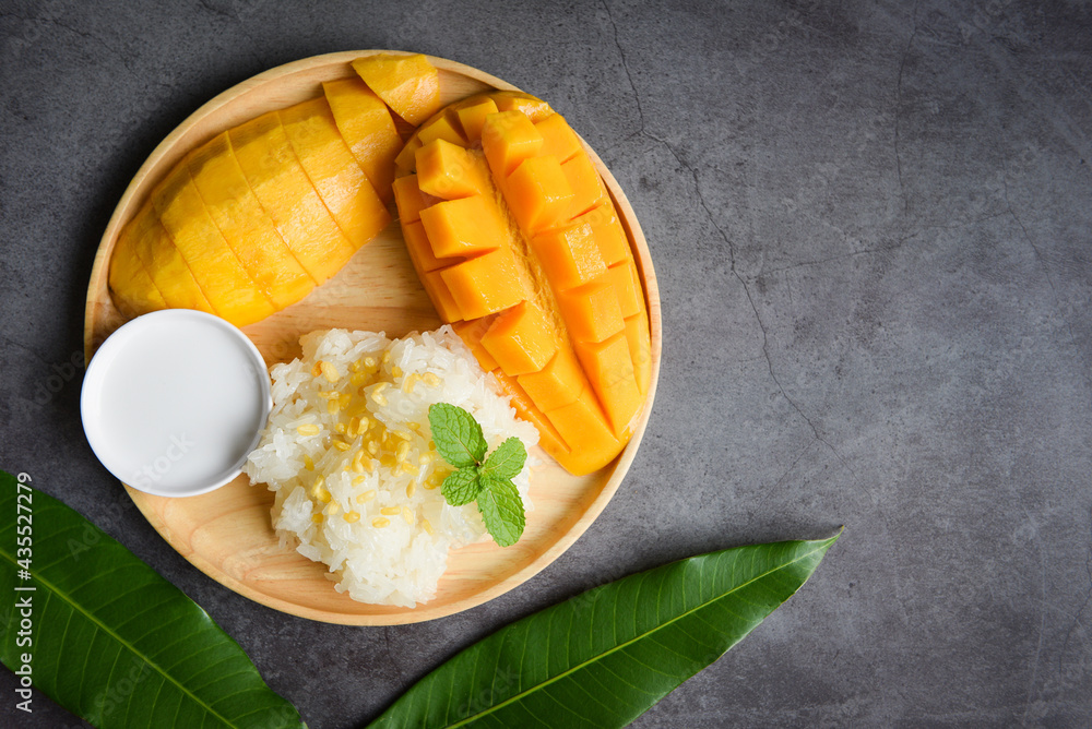 Ripe mango rice cooked with coconut milk, Sticky rice summer tropical fruit food Asian Thai dessert sweet mango peel and sliced on plate and fresh mint leaves