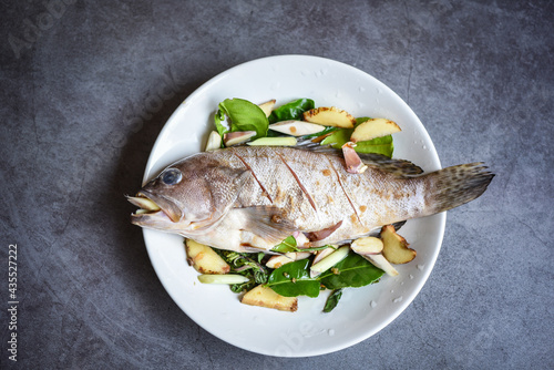 Foto Fresh raw grouper fish on plate with herbs and spices for cooked food seafood st