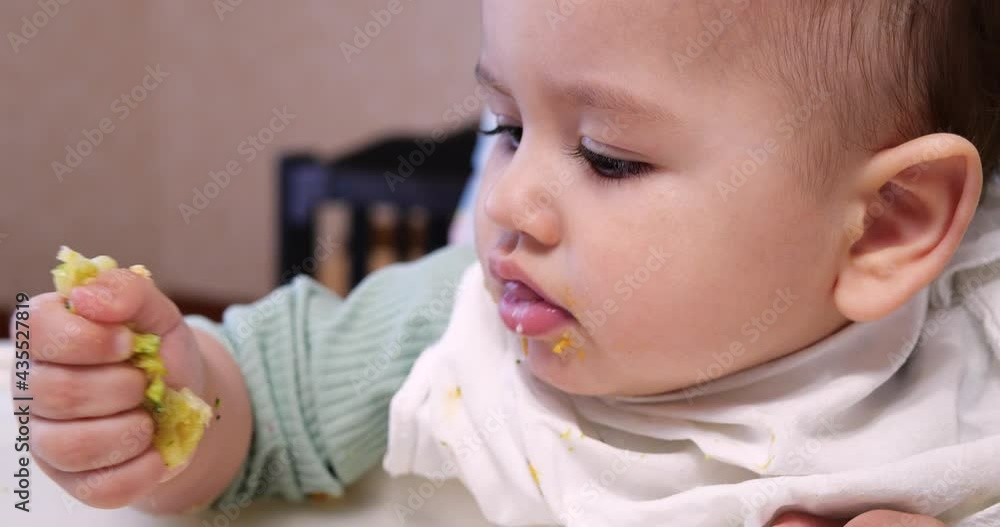 Mom feeds the boy with a spoon and hand, family food and parenthood concept. first complementary foods and self-feeding Mom feeds the boy with a spoon and hand, family food and parenthood concept. first complementary foods and self-feeding