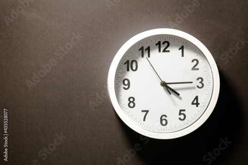 Modern white Wall Clock with black time pointer off center on black background. Shadows on the Clock Face. Concept Clock design with copy space for your own text. Business Clock show the day time