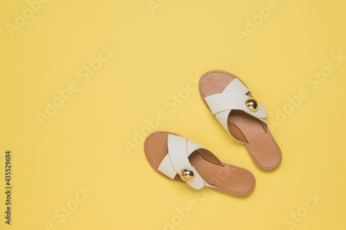 Top view of yellow leather sandals on a yellow background. photo