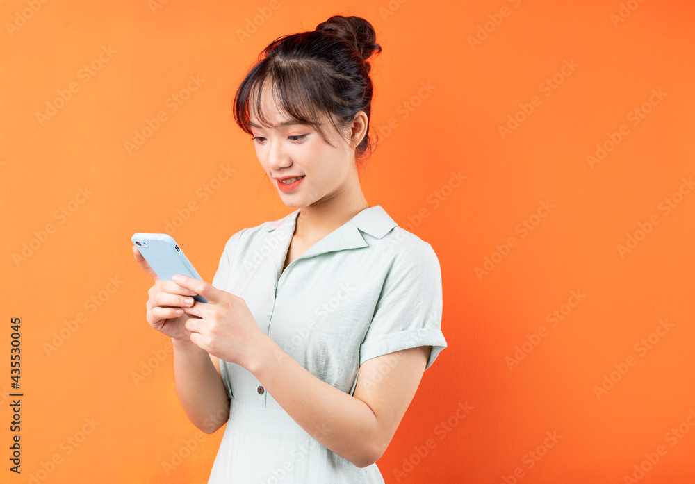 Portrait of young girl using mobile phone, isolated on orange background Portrait of young girl using mobile phone, isolated on orange background