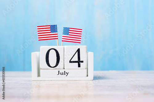 Wooden calendar of July 4th with miniature United States of America flag on wood background. Independence day and nation Holiday concept photo