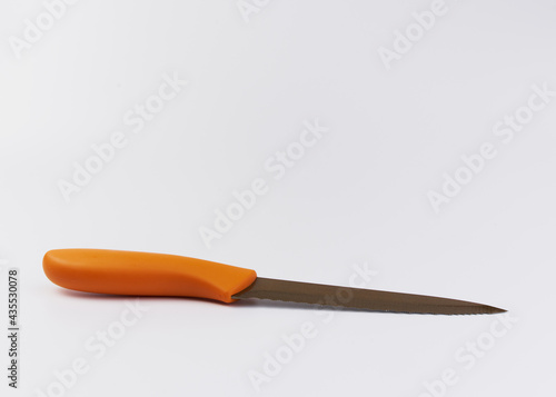 Un cuchillo de cocina de color naranja sobre un fondo blanco