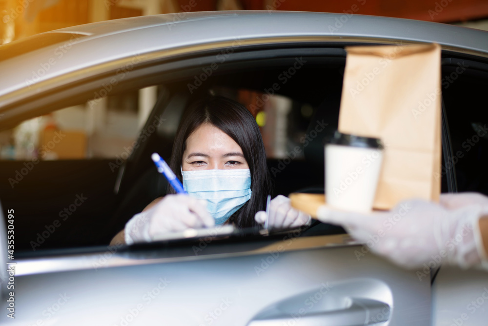 Woman sign for delivery food in car,Safety food during coronavirus pandemic situation,Drive thru service Woman sign for delivery food in car,Safety food during coronavirus pandemic situation,Drive thru service