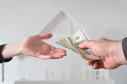 Two people passing money against a white house