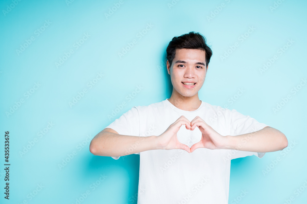Handsome asian guy showing heart with hands and smiling while looking at camera Handsome asian guy showing heart with hands and smiling while looking at camera