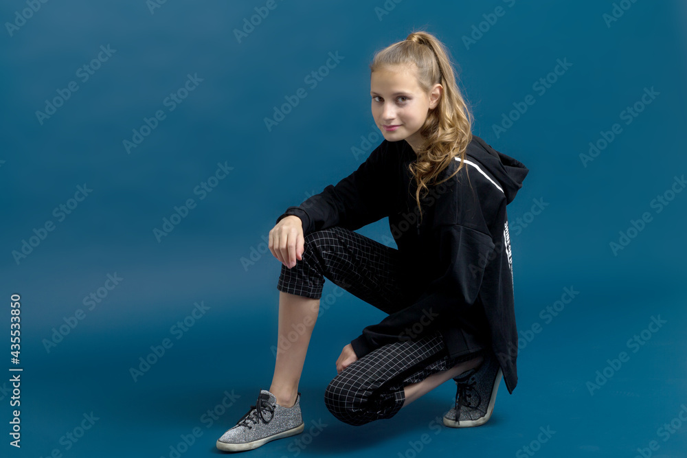 Obraz premium Teen girl in black hoodie sitting on floor