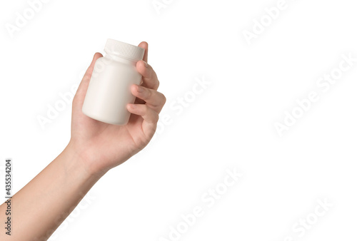 Hand holding a white plastic medicine bottle on white background. photo