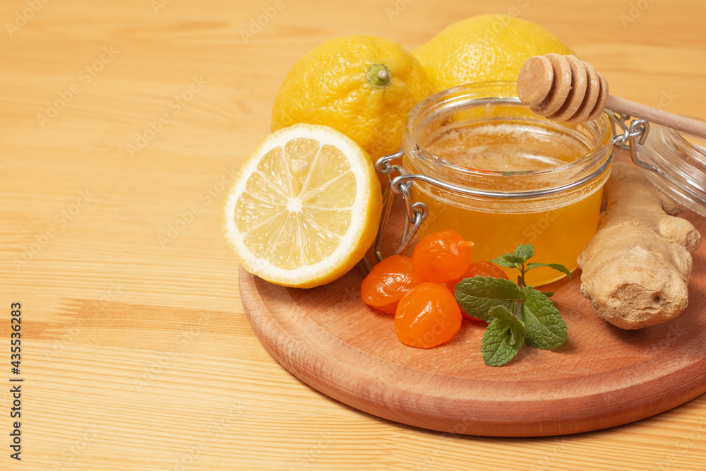 Ginger root, mint, lemon and liquid honey in honey-jar. Wooden background. Healthy food. Selective focus. Ginger root, mint, lemon and liquid honey in honey-jar. Wooden background. Healthy food. Selective focus.