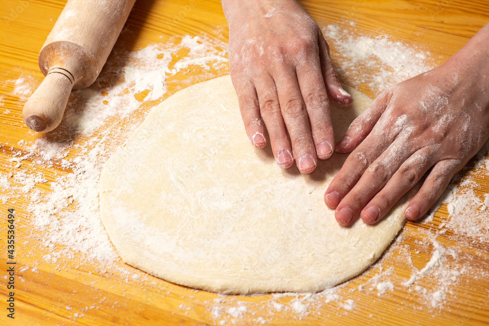 Hands with rolling-pin make dough for pizza. Italian pizza cooking preparation process on wood table. Pizza dough Hands with rolling-pin make dough for pizza. Italian pizza cooking preparation process on wood table. Pizza dough