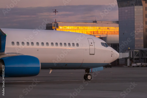 A close-up of the front of a passenger airplane. The aircraft is taxiing at the airport apron near the terminal