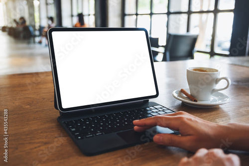 Mockup image of a woman using and touching on digital tablet touchpad with blank white desktop screen in cafe