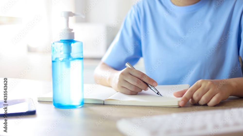 Young Asian woman wearing medical facial handmade mask working alone distancing policy with. Hand sanitizer gel during coronavirus or covid-19 virus outbreak a new normal concept. Young Asian woman wearing medical facial handmade mask working alone distancing policy with. Hand sanitizer gel during coronavirus or covid-19 virus outbreak a new normal concept.