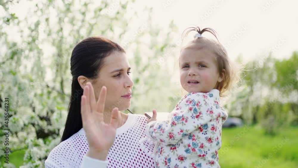 mother with a daughter in her arms say goodbye, say while and wave her hand mother with a daughter in her arms say goodbye, say while and wave her hand