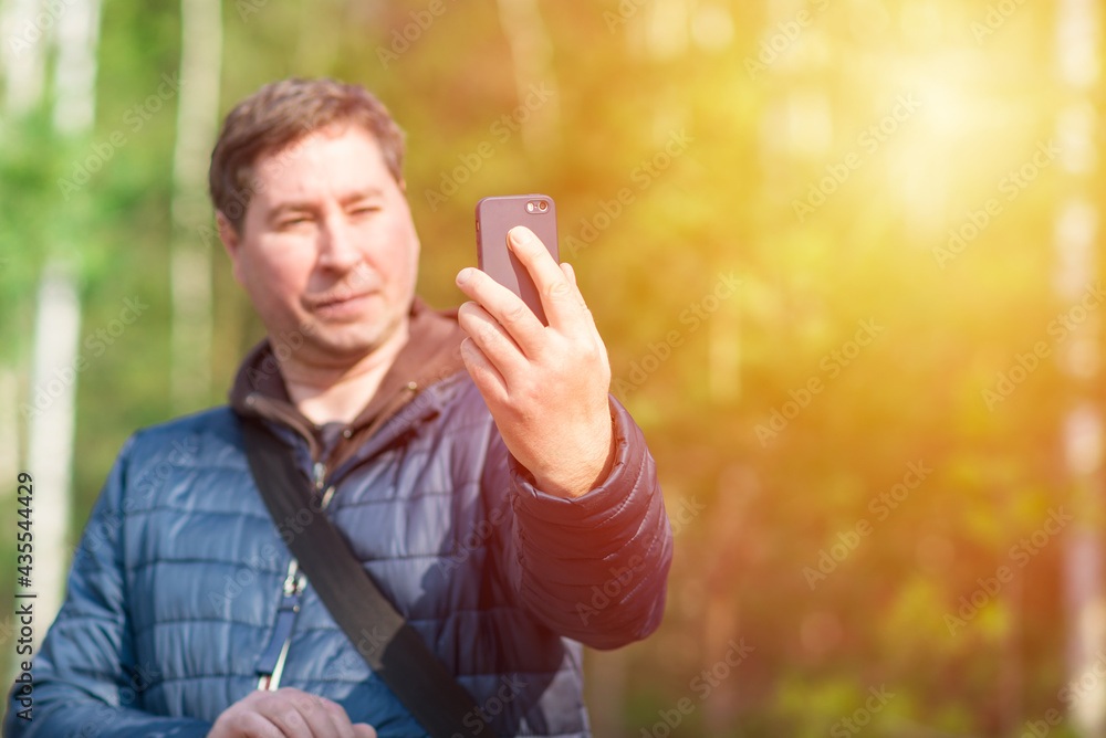 One 40s man with his mobile smart phone searching for reception signal in the sunny forest. One 40s man with his mobile smart phone searching for reception signal in the sunny forest.