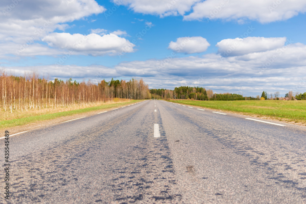 Asphalt road field and forest sunny white cloud blue sky shot.