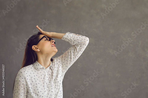 Young caucasian woman touching forehead regrets wrong doing studio shot. Silly millennial slapping hand on head having duh moment. Negative human emotion. Headshot portrait with copy space photo