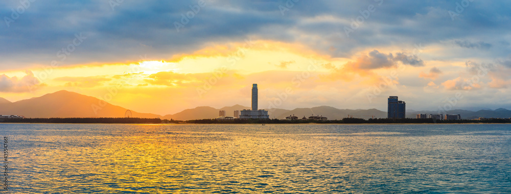 Beautiful sea water and mountains with city skyline at sunset.