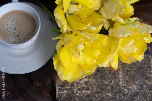 Still life. Yellow and orange tulips, cup of coffee and old book. Concept of congratulation