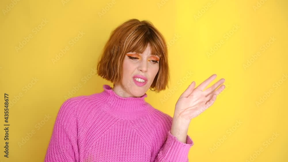 A girl standing in front of a yellow background with short hair and a pink sweater. She have bored and disagree. She look at around and she is denying with her head. Emotion. Facial Expression. A girl standing in front of a yellow background with short hair and a pink sweater. She have bored and disagree. She look at around and she is denying with her head. Emotion. Facial Expression.