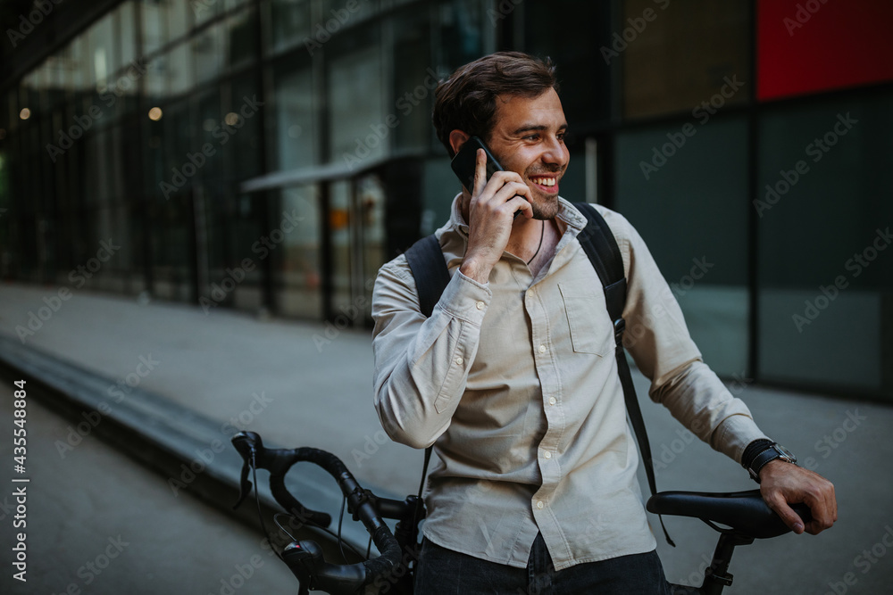 Fototapeta premium Businessman commuting to work with his bicycle and talking on phone
