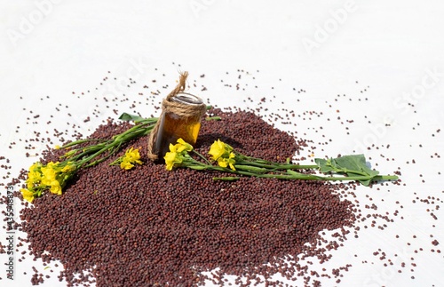 Mustard Oil in Small Glass Jar Amid Black Mustard Seed and Yellow Flower with Selective Focus and Copy Space photo